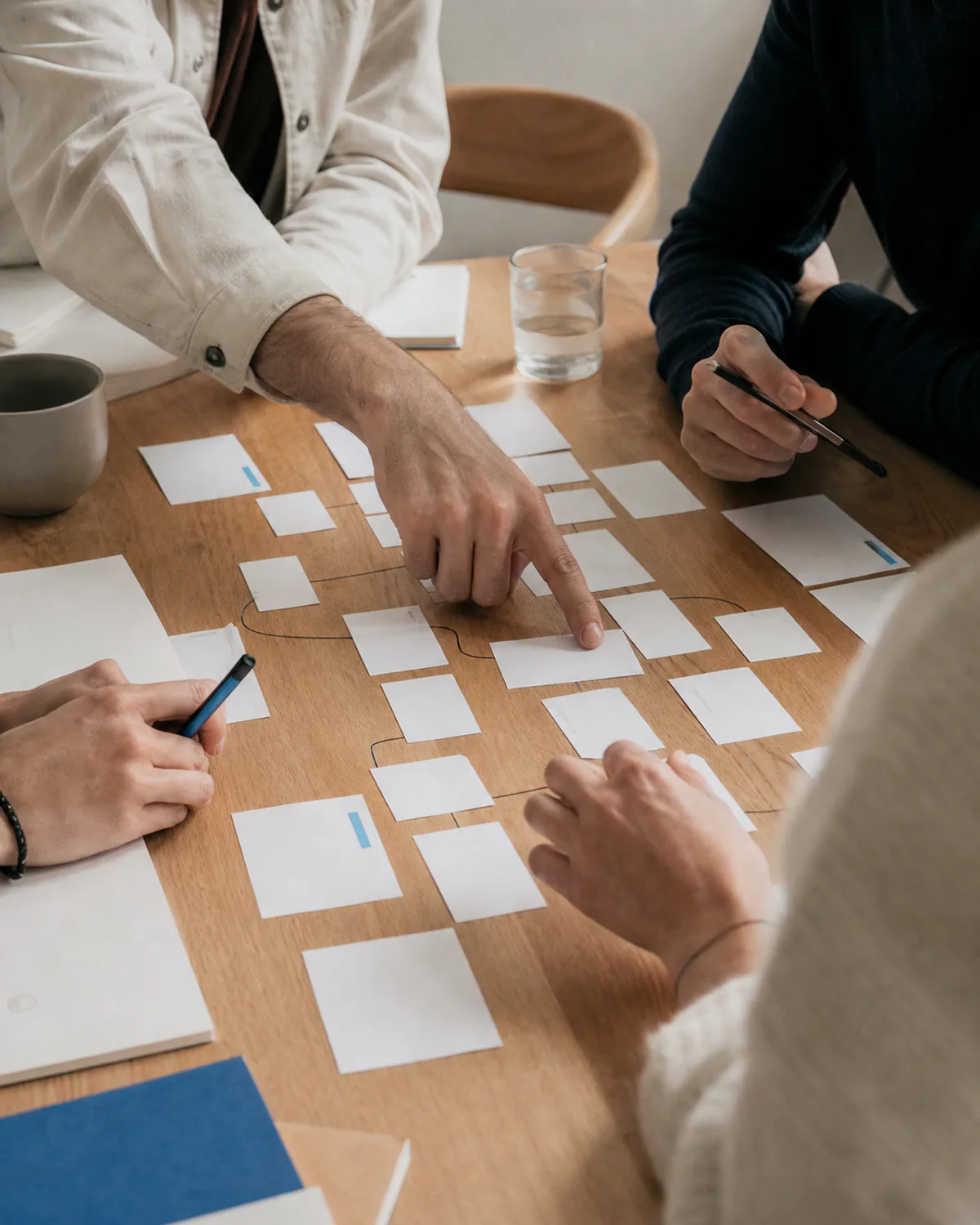 Hands arranging call flows and notes on a bright workshop table